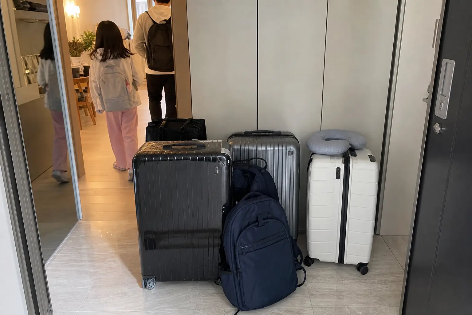 현관 앞에 큰 캐리어 여러 개를 세워두고 해외여행 출발을 준비하는 가족의 아침